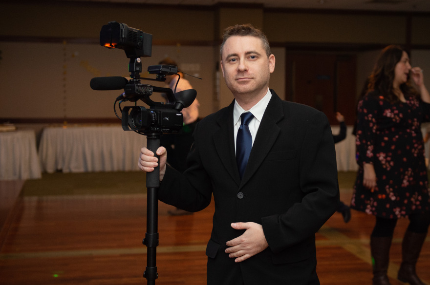 A man in a suit holding a video camera.