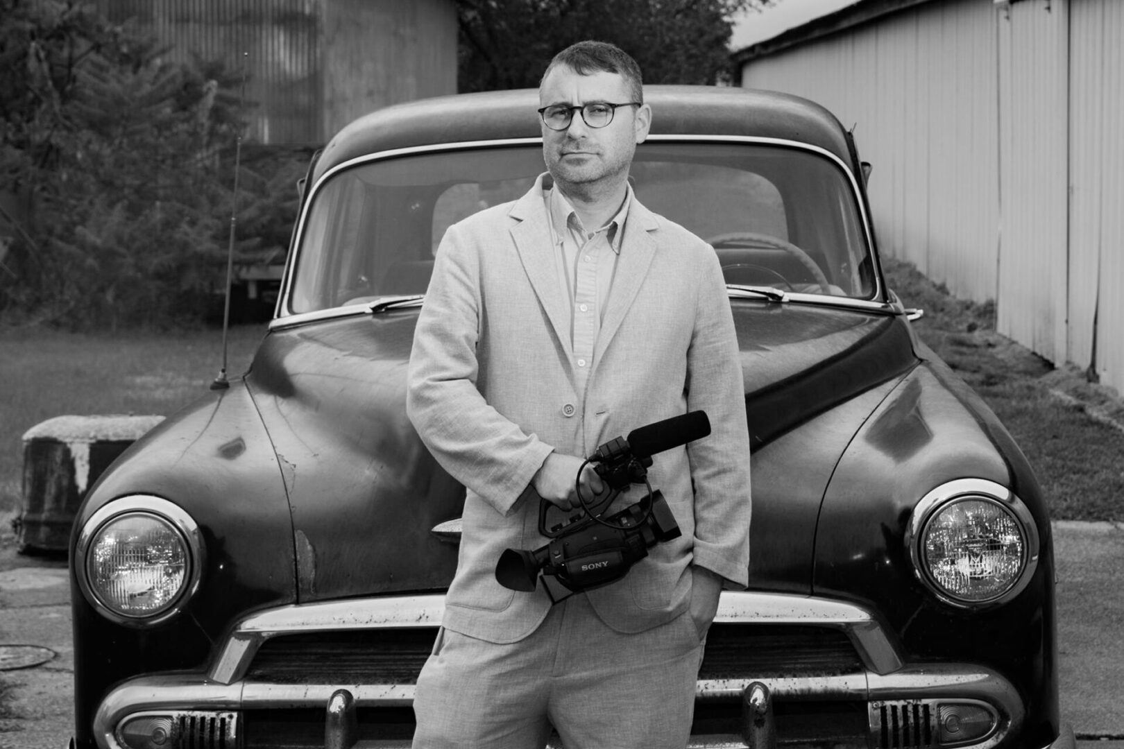 A man in suit and tie standing next to an old car.