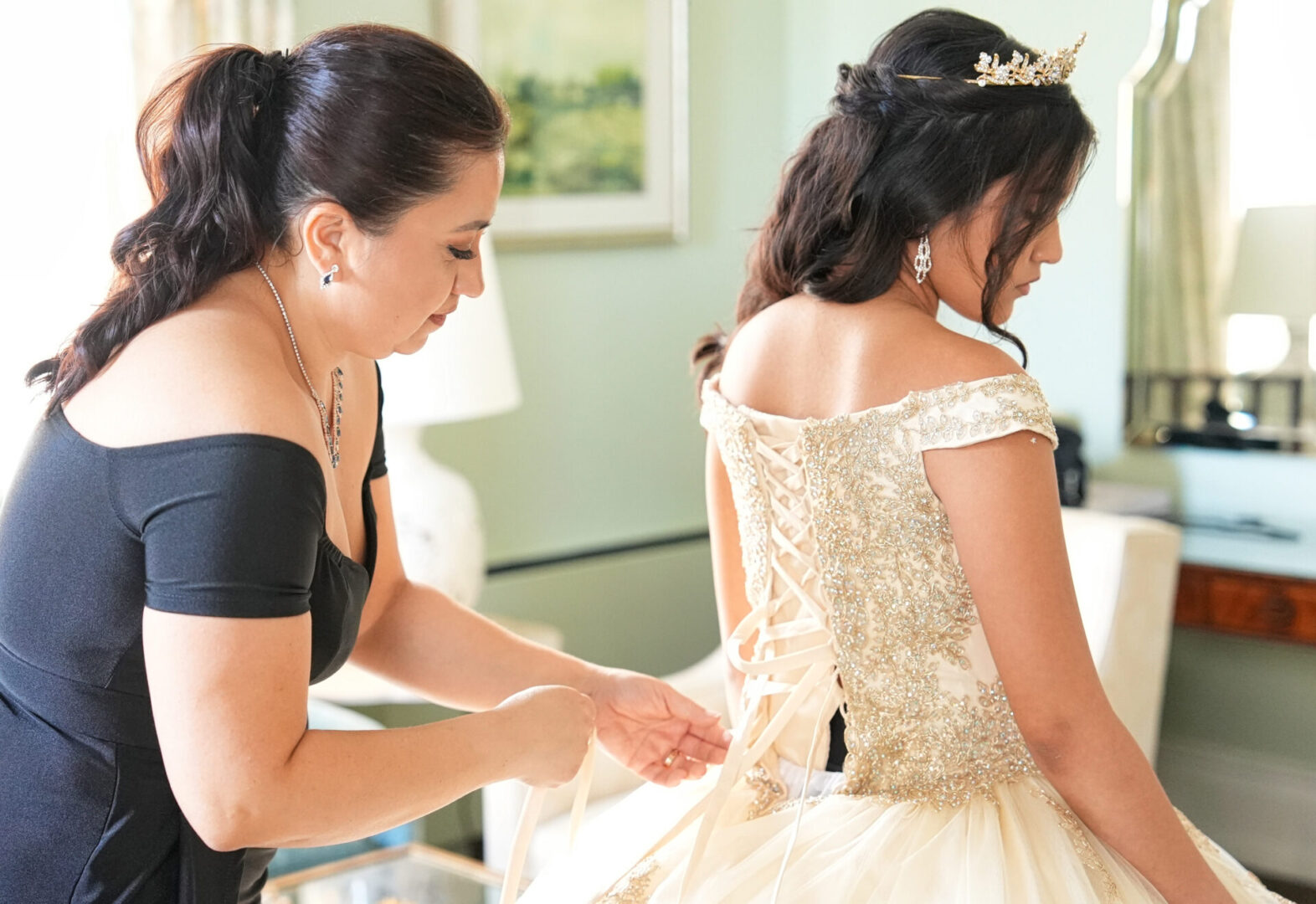A woman helping another girl put on her dress.